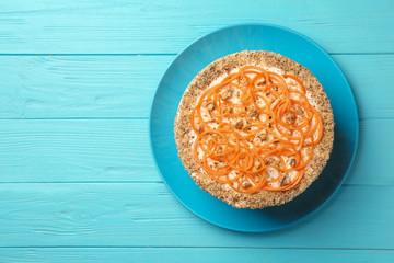 Dish with delicious carrot cake on blue wooden background, top view. Space for text