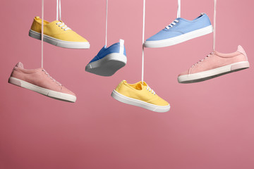 Bright stylish shoes hanging against color background