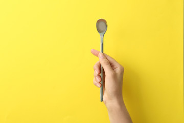 Woman holding empty soda spoon on color background, closeup. Space for text
