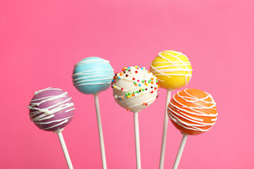 Many bright delicious cake pops on color background