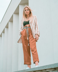 Beautiful girl posing on the street near the walls of a high building.