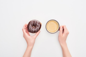 cropped view of woman holding tasty glazed chocolate doughnut and coffee cup on white background