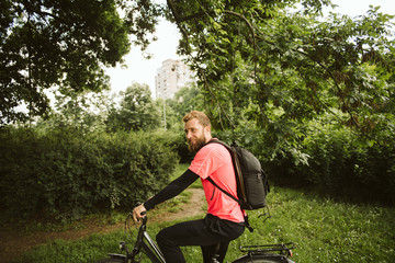 Fototapeta premium A handsome young man riding a bicycle in the park