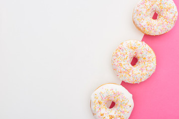 top view of tasty glazed doughnuts on white and pink background