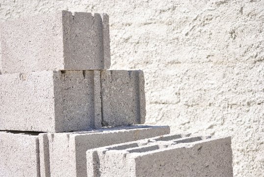 Group of concrete blocks used in construction. With concrete wall on the background.
