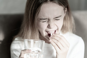 Girl taking pill. Feeling sick. Young girl eating drug. Healthcare and medical concept
