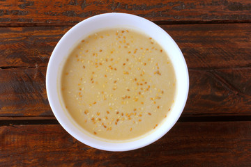 Tahini in ceramic bowl on rustic wooden table- cream or paste made from sesame seeds (sesame) widely used in Middle Eastern cuisine