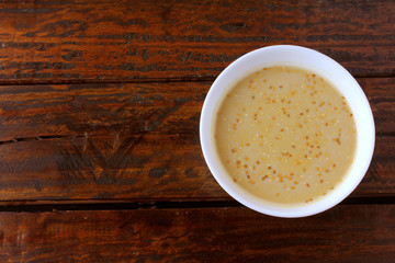 Tahini in ceramic bowl on rustic wooden table- cream or paste made from sesame seeds (sesame) widely used in Middle Eastern cuisine