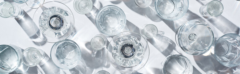 top view of transparent glasses with water on white background, panoramic shot