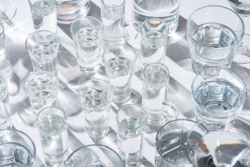 close up view of transparent glasses with water on white background with shadows