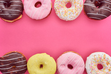 top view of tasty glazed doughnuts on pink background with copy space