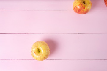 Set of red and yellow apples on pink background