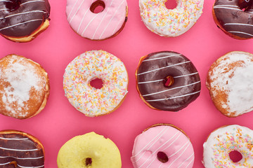 top view of tasty glazed colorful doughnuts on bright pink background