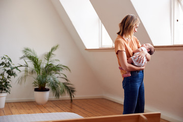 Loving Mother Holding Newborn Baby At Home In Loft Apartment