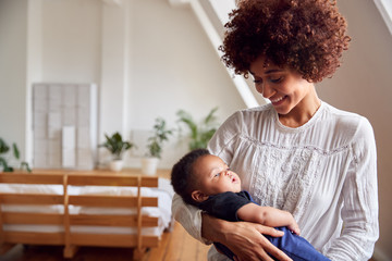 Loving Mother Holding Newborn Baby At Home In Loft Apartment