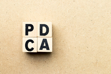 Alphabet letter block in word PDCA (business abbreviation of plan do check act) on wood background