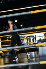 Obraz premium selective focus of boxing ring surrounded by ropes near man exercising in boxing gloves