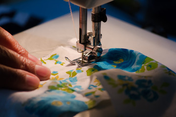 Woman using sewing machine, closeup. Women's hands behind her sewing,selective focus