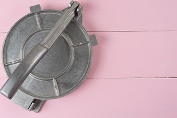 Metallic manual machine tortilla press on pink background