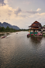 Fototapeta premium Laos, Van Vieng city landscape with river and mountains and boat, kayak on the water