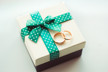 Wedding rings on a gift box with a green ribbon