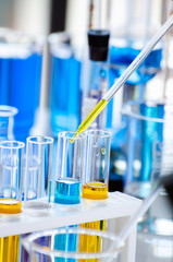 A pipette dropping sample into a test tube,abstract science background