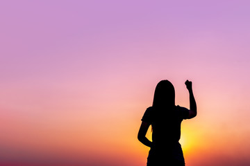 Woman raising her fist in the air in the morning.