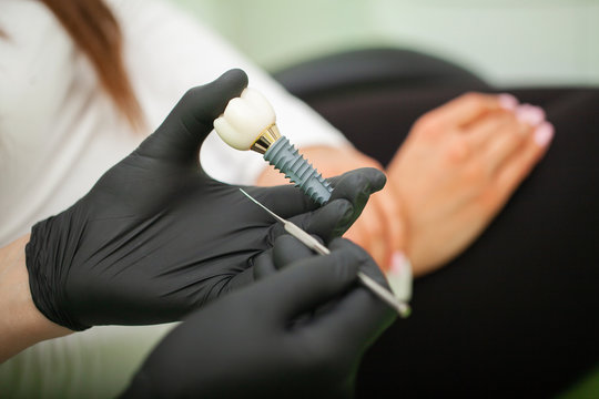 Dentist explaining teeth model to female patient. Technical shots on a dental prothetic laboratory