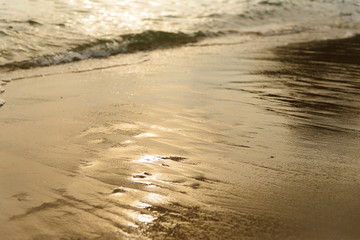 Golden light reflecting off a water wave at the sea and sand on sunset. Pure Gold