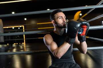 athletic man in boxing gloves drinking water in sports center