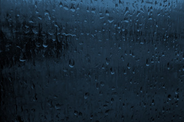 Rain drops on blue glasses surface or  metal. Pattern of raindrops. Water drops on glass texture background. Little blurred. Banner for text.