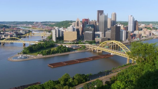 An evening time lapse view of the iconic Pittsburgh skyline as seen from Mt. Washington. A coal barge passes under the Fort Pitt Bridge.  	