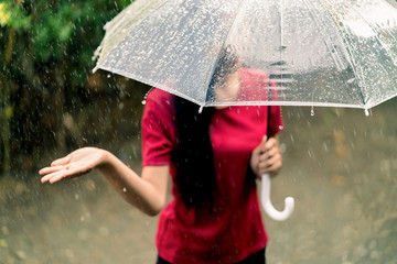 Young asian woman smiling and enjoying under umbrella in rainy season.