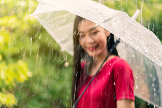 Young asian woman smiling with happiness under umbrella in rainy season.