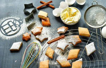 cookies in the shape of stars and diamonds on a dark background. ingredients for cookies butter, sugar, flour, recipe. the symbol of the gift of powdered sugar. Top view on gray stone table
