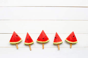 Watermelon slice popsicles on white wooden background.