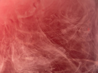 Drop of pink paint in water, abstract background. Close up view. Blurred background. Acrylic clouds swirling under water, abstract pattern. Paint mixing with liquid. Pink smoke, abstraction