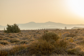 Sun sets over the mountains and bushy hills at a beach in the island of Naxos.