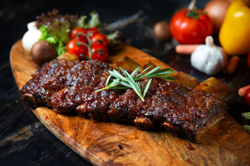  BBQ beef ribs steak served with a hot chili pepper and fresh tomatoes on an old vintage wooden cutting board