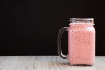 Mason glass jar mug filled with strawberry banana smoothie, side view. Copy space. Close-up.