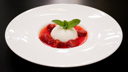 Pana cotta with strawberry and mint topping with strawberry sauce.