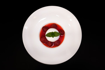 Pana cotta with strawberry and mint topping with strawberry sauce.