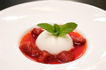 Closed up of Pana cotta with strawberry and mint topping with strawberry sauce, selective focus.
