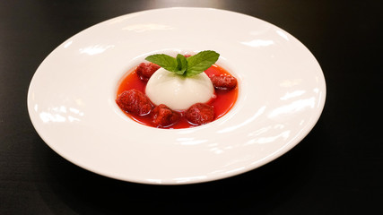 Pana cotta with strawberry and mint topping with strawberry sauce.