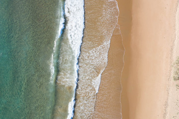 Aerial top shot of a beach with nice sand, blue turquoise water and tropical vibe