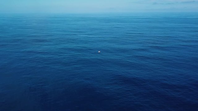 Drone Shot closing in on a boat stranded in the middle of the deep blue sea.