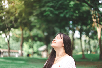 Asian young woman smiling enjoying relaxing feeling breathing fresh air in public park