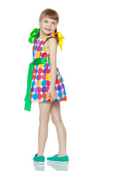 A little girl in a dress with a pattern from multi-colored circl