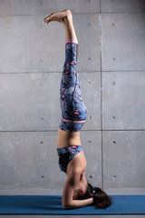 girl performs headstand, yoga exercises, the concept of sport