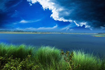 River and dark cloud with colorful green grass